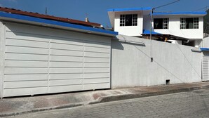 Un bâtiment avec une porte de garage blanche, un toit rouge et des bordures bleues.