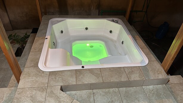 Un jacuzzi rectangulaire à l’intérieur vert, entouré d’un sol carrelé.