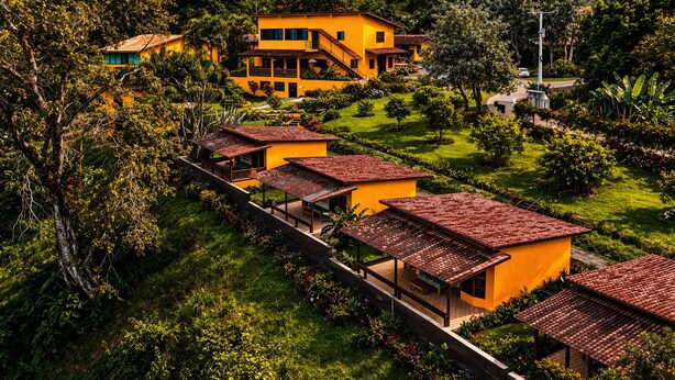 Un bâtiment jaune doté de nombreux balcons et d’un jardin.
