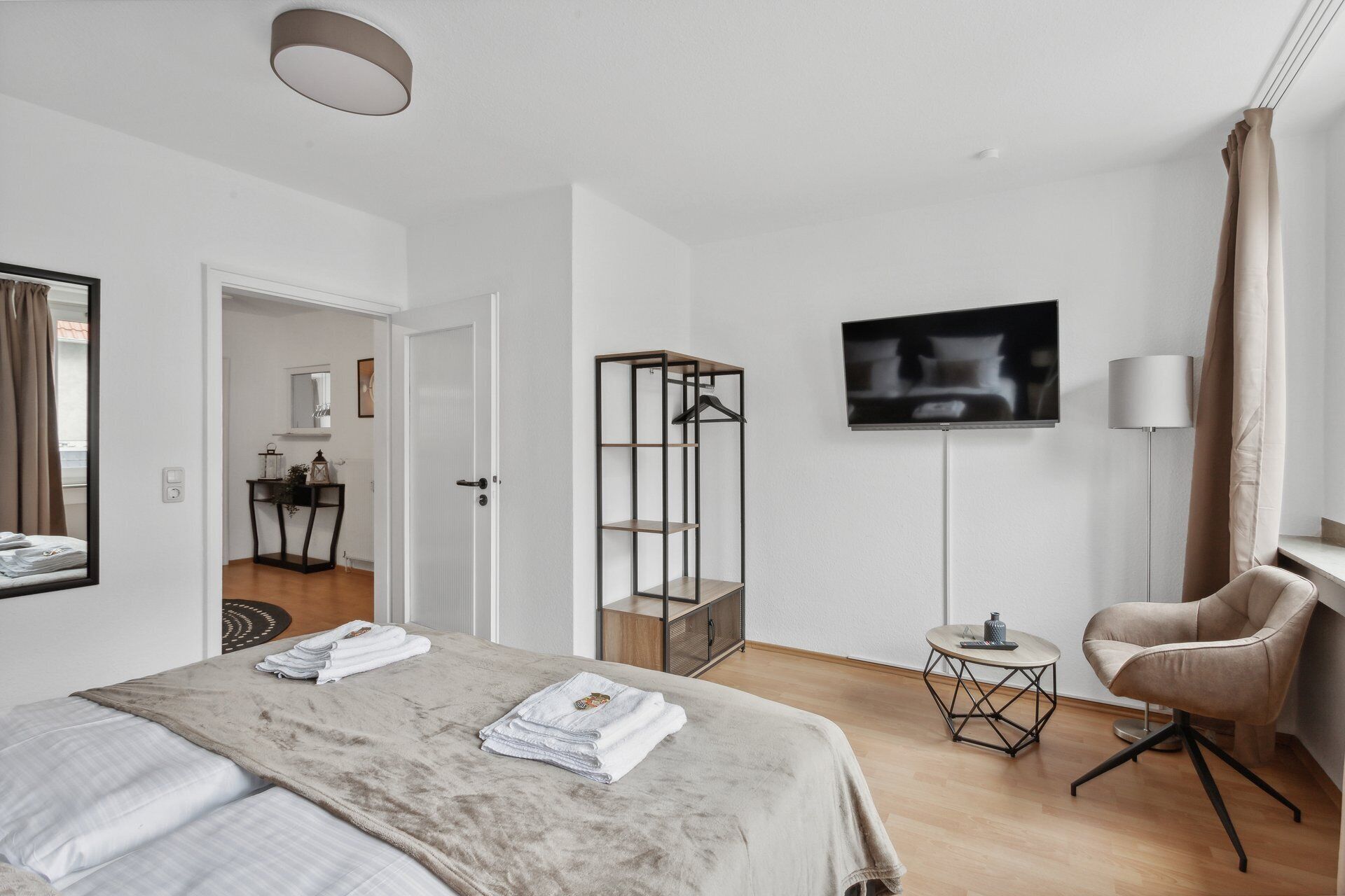 Een moderne hotelkamer met een bed, een televisie, een stoel en een tafeltje.