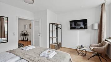 Een moderne hotelkamer met een bed, een televisie, een stoel en een tafeltje.