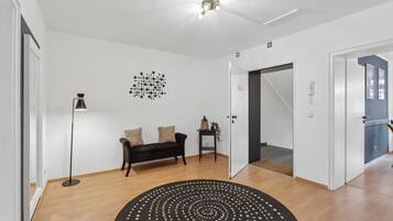 Un intérieur moderne avec un canapé noir, un lampadaire et un tapis à motifs.