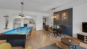 Ein modernes Wohnzimmer mit Billardtisch, Essbereich und Küche.