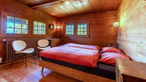 A wooden cabin bedroom with a bed, two chairs, a desk, and a radiator. - Supersaxo QUIET & CHARMING chalet 10 pers (Veysonnaz)