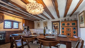 A rustic dining area with wooden furniture, a large wooden table set for six, and a unique ceiling light fixture. - Supersaxo QUIET & CHARMING chalet 10 pers (Veysonnaz)