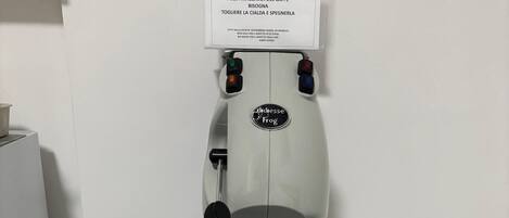 A coffee machine on a white stand with a label, a power outlet, and a cable.