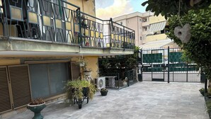 A courtyard with potted plants, a tiled floor, and a gated entrance. - B&B il girasole (Maddaloni)
