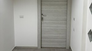 A hallway with a wooden door, light-colored walls, and a light wood floor. - B&B il girasole (Maddaloni)