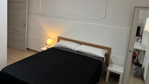 A bedroom with a bed, bedside table, lamp, wardrobe, and an air conditioning unit. - B&B il girasole (Maddaloni)