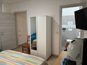Une chambre à coucher comprenant un lit, une armoire, une chaise, un bureau et un téléviseur.