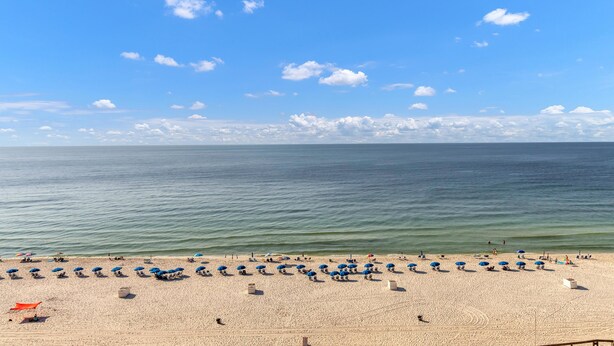 A beach with rows of umbrellas and sun loungers, a clear sky, and calm sea. - Phoenix I 1097 (Orange Beach)