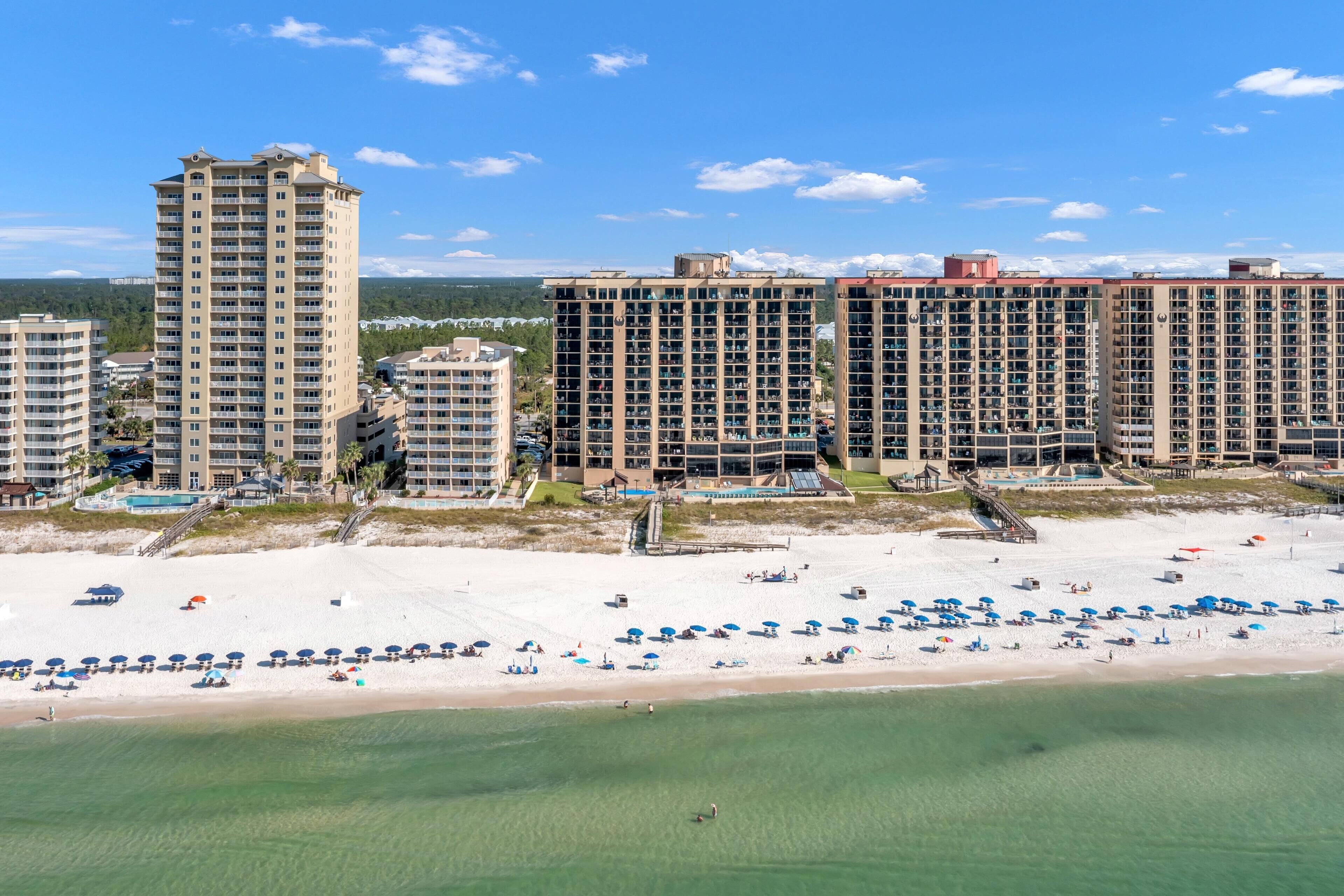 Ein Strandhotel mit mehreren Hochhäusern, einem Sandstrand und blauem Himmel.