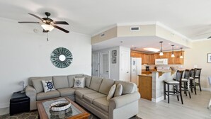 A modern living room with a sectional sofa, a coffee table, and a ceiling fan.