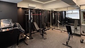 A gym with exercise equipment, a digital scale, and a mirror wall. - Hotel Portal Central (Itagüí)