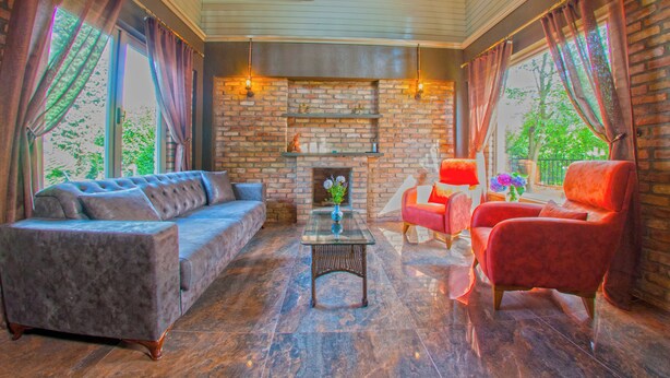 Una sala de estar acogedora con una chimenea de ladrillo, un sofá mullido, un sillón rojo y una mesita de centro.