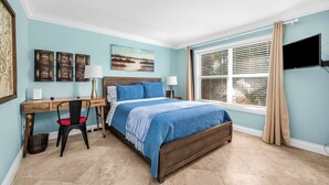 Un dormitorio con cama, escritorio, silla y una obra de arte en la pared.