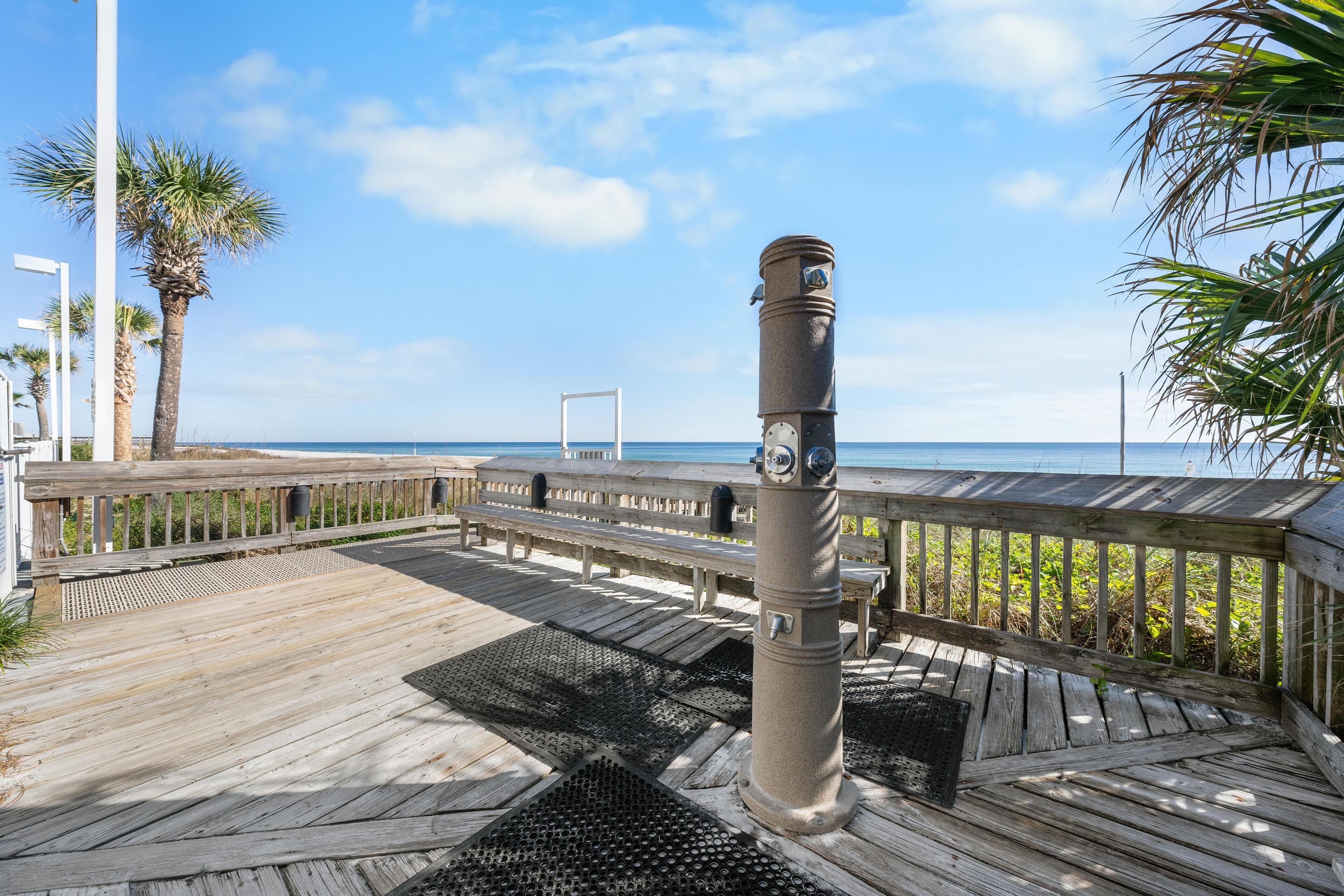 A wooden deck with a metal pole, benches, and a view of the ocean.