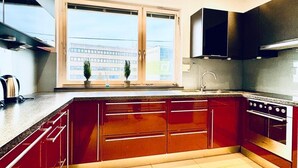 Una cucina moderna con armadietti rossi, un forno in acciaio inossidabile e un'ampia finestra con vista sulla città.