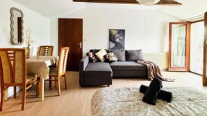 Una camera da letto con un letto, un divano, un tavolo da pranzo e sedie, e una ventola a soffitto.