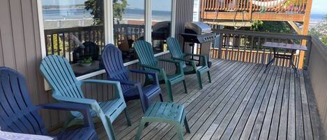 Een terras met Adirondack-stoelen, een barbecue en uitzicht op de oceaan.