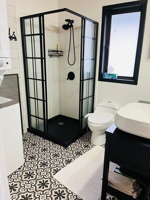A bathroom with a glass-enclosed shower, a toilet, and a sink. - Charming, dog-friendly cabin in peaceful Birch Bay, Wa (Blaine)