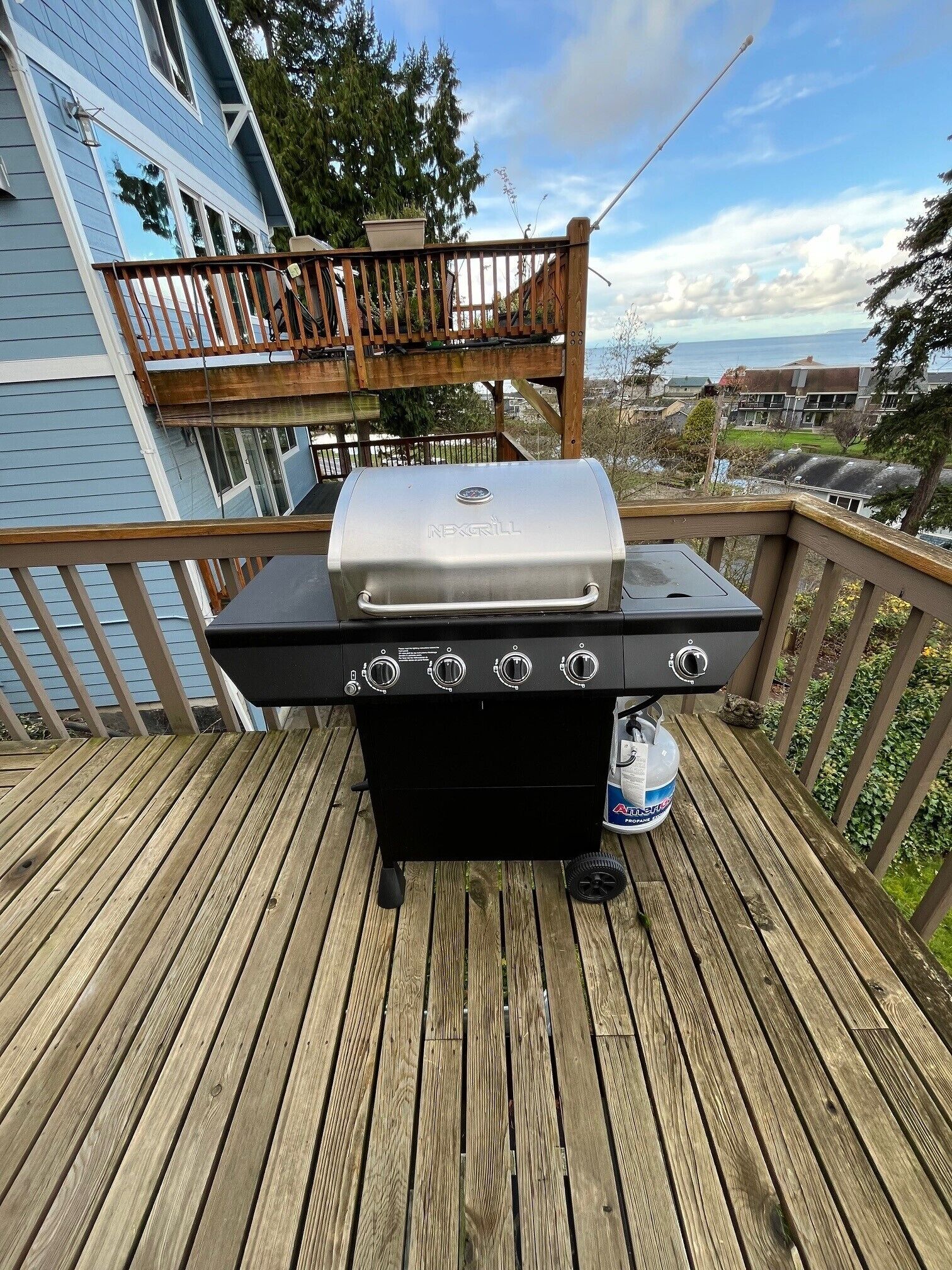 Un barbecue noir pour l’extérieur, doté de quatre brûleurs, installé sur une terrasse en bois.