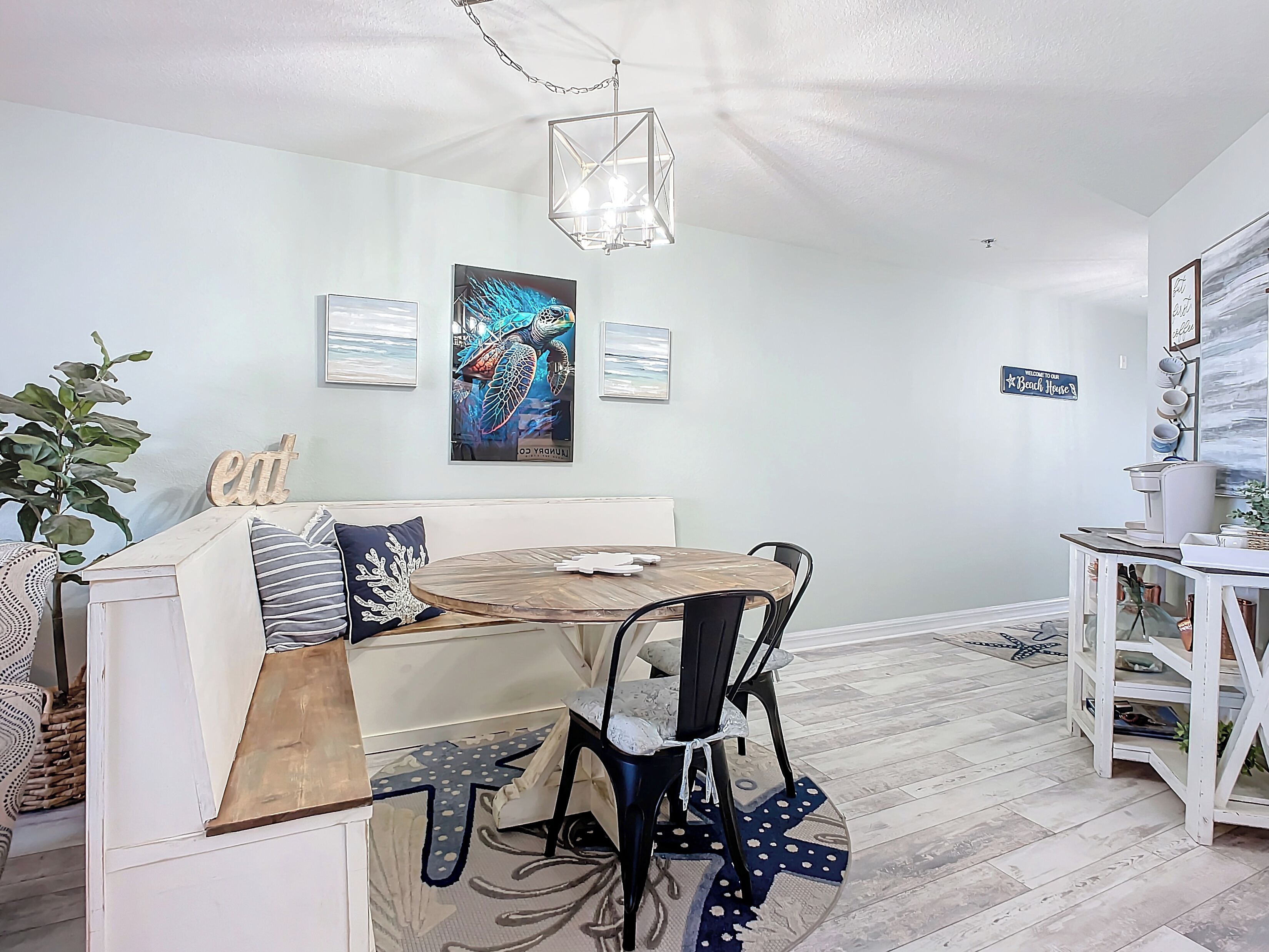 A modern dining area with a round table, chairs, and a decorative ceiling light.