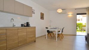 Cocina moderna con comedor, que incluye una mesa y sillas blancas, cafetera y lavamanos.