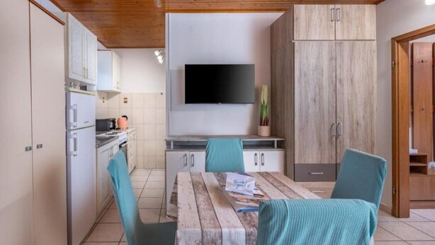 Une cuisine moderne avec un coin repas, des meubles en bois, un téléviseur à écran plat et une table avec des chaises.