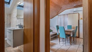Une cuisine compacte dotée d’un évier et de placards intégrés, un coin repas avec une table et des chaises, et un plafond en pente avec des poutres en bois.