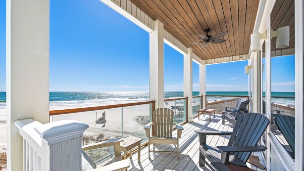 A wooden deck with chairs and tables overlooking a beach. - 5-Bed Beach House with Private Pool (Panama City Beach)