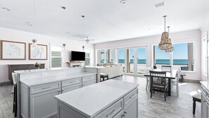 A spacious kitchen with a large island, a dining area with a view of the ocean, and a living area with a fireplace. - 5-Bed Beach House with Private Pool (Panama City Beach)