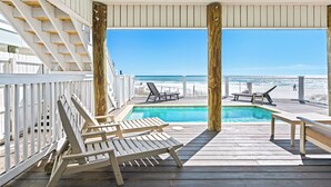 A wooden deck with a pool and lounge chairs overlooking a beach. - 5-Bed Beach House with Private Pool (Panama City Beach)