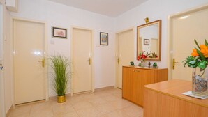 Ein Flur mit drei Türen, einem Holzschrank mit Spiegel und einem Blumentopf.