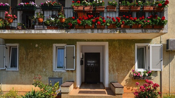Ein zweistöckiges Gebäude mit einem Balkon, der mit Blumentöpfen und Blumen geschmückt ist.