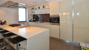A modern kitchen with a central island, bar stools, a built-in oven, and a window providing natural light. - Sophisticated and Chic Villa with Pool - Four Bedroom Villa with Pool (Kanfanar)