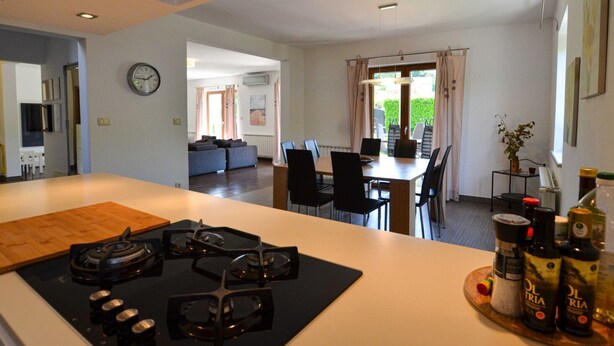 A modern kitchen with a central island, dining area with chairs, and a view to a garden. - Sophisticated and Chic Villa with Pool - Four Bedroom Villa with Pool (Kanfanar)