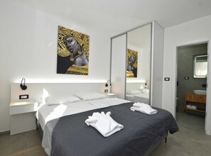 Relax in a spacious room with a large bed, bedside table, and wall-mounted clock.