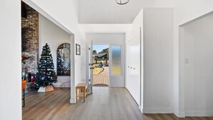 Un couloir décoré d’un sapin de Noël, doté d’un plancher en bois et offrant une vue sur une terrasse extérieure.