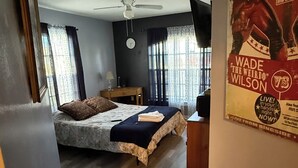 A bedroom with a bed, a ceiling fan, a window, and a poster on the wall.