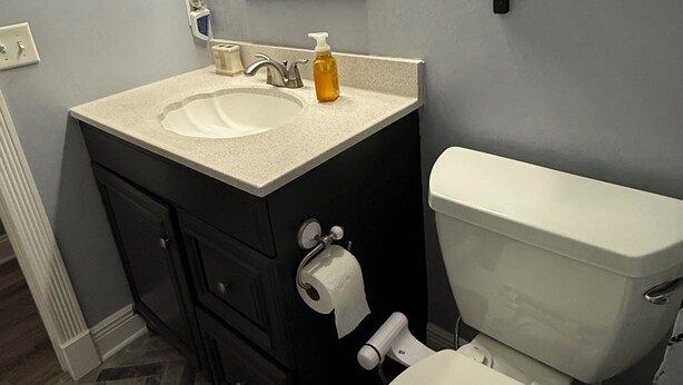 Un bagno con una toeletta, lavabo, specchio, WC e un lampadario sopra lo specchio.