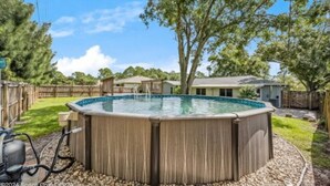 A hot tub in a backyard with a wooden deck, surrounded by trees and a small shed.