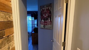 A hallway with wooden walls, a poster on the wall, and a door at the end.