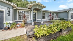 Una casa a due piani con un portico coperto, un garage e un giardino curato.