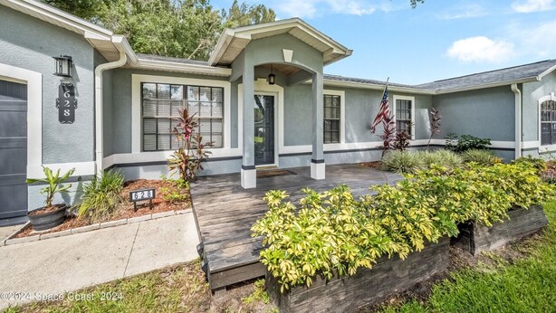 A two-story house with a covered front porch, a garage, and a well-maintained garden.