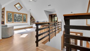 A spacious loft with high ceilings, large windows, a wooden staircase, and a cozy seating area. - Big Sam's Riverside Retreat (Stanfield)