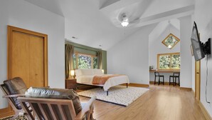 A bedroom with a bed, a desk, a chair, and a TV mounted on the wall. - Big Sam's Riverside Retreat (Stanfield)
