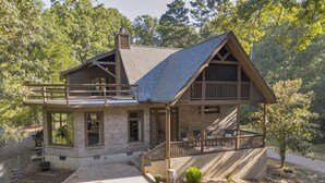 A two-story log cabin with a balcony, a covered porch, and a stone foundation. - Big Sam's Riverside Retreat (Stanfield)