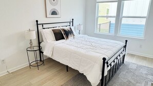 Une chambre à coucher avec un lit, un ventilateur de plafond, une fenêtre et un tapis.