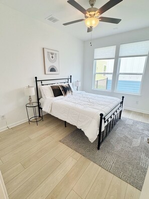 Ein Schlafzimmer mit Bett, Deckenventilator, Fenster und Teppich.
